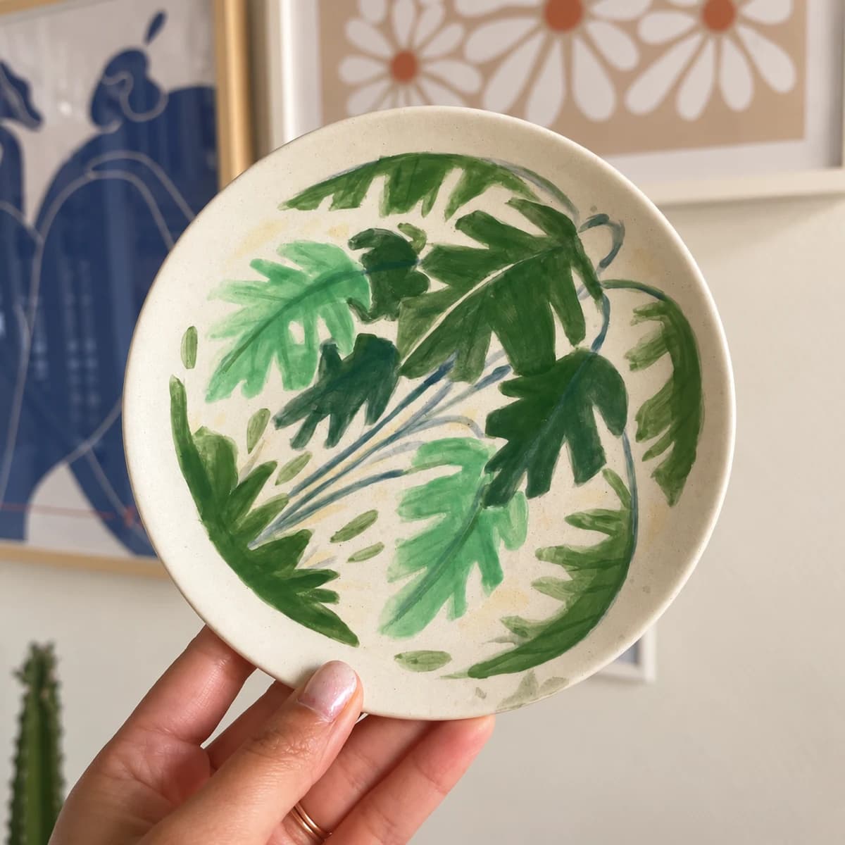 Assiette tenue à la main peinte de grandes feuilles dans plusieurs tons de vert